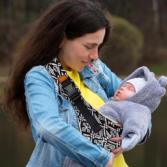 maman regarde bébé allongé dans écharpe de portage bébé